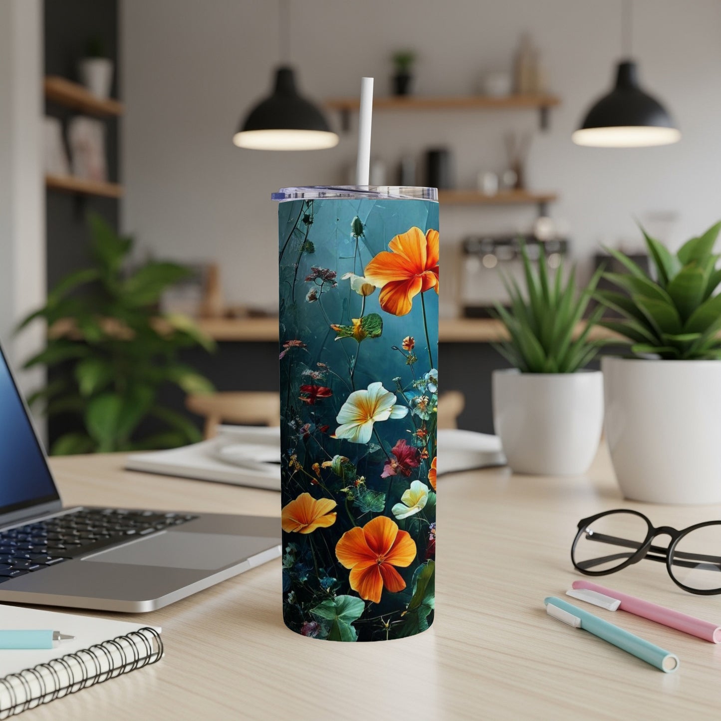 Tumbler with colorful wildflowers and greenery on a desk.