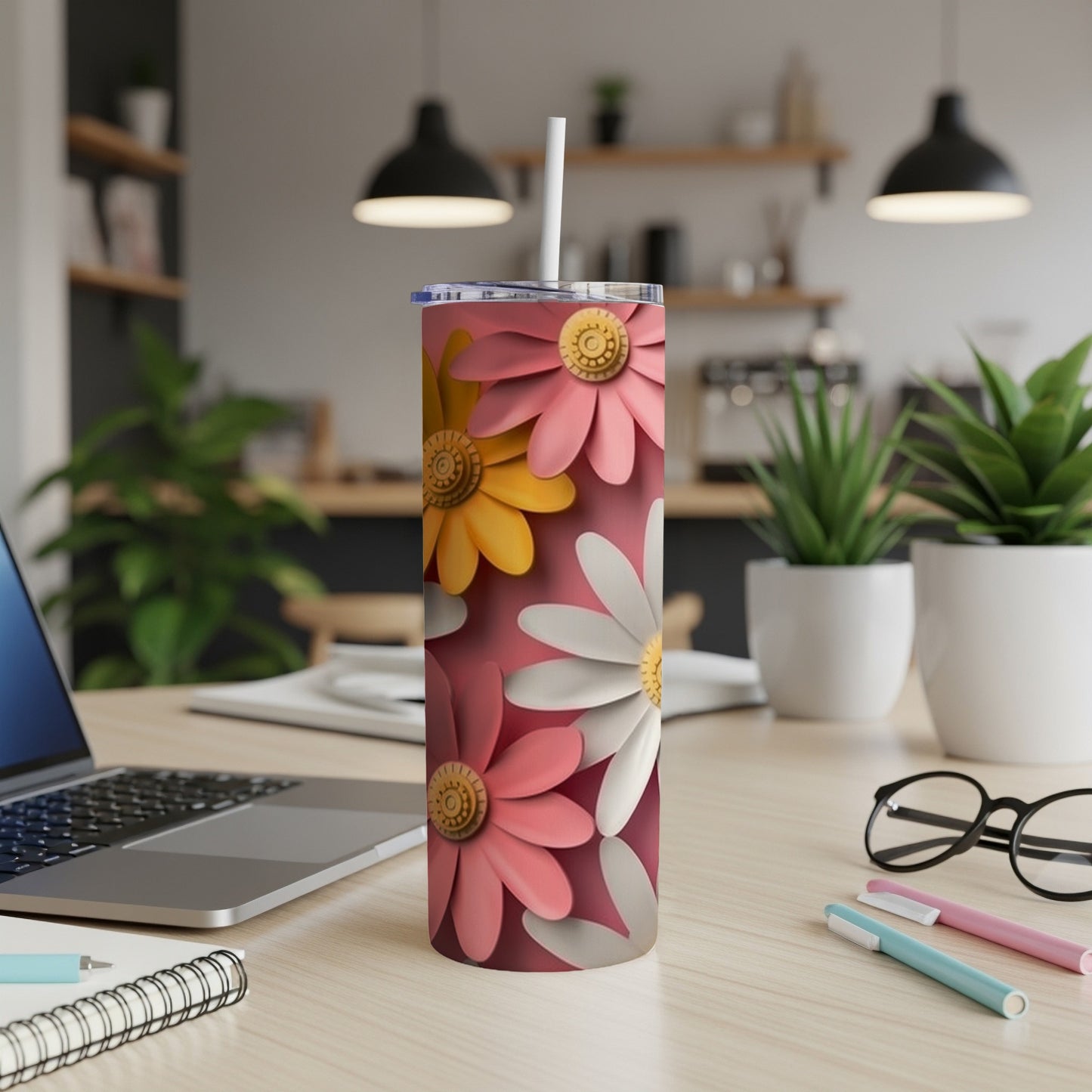 Pink, yellow, and white daisies decorate a skinny tumbler with a straw.