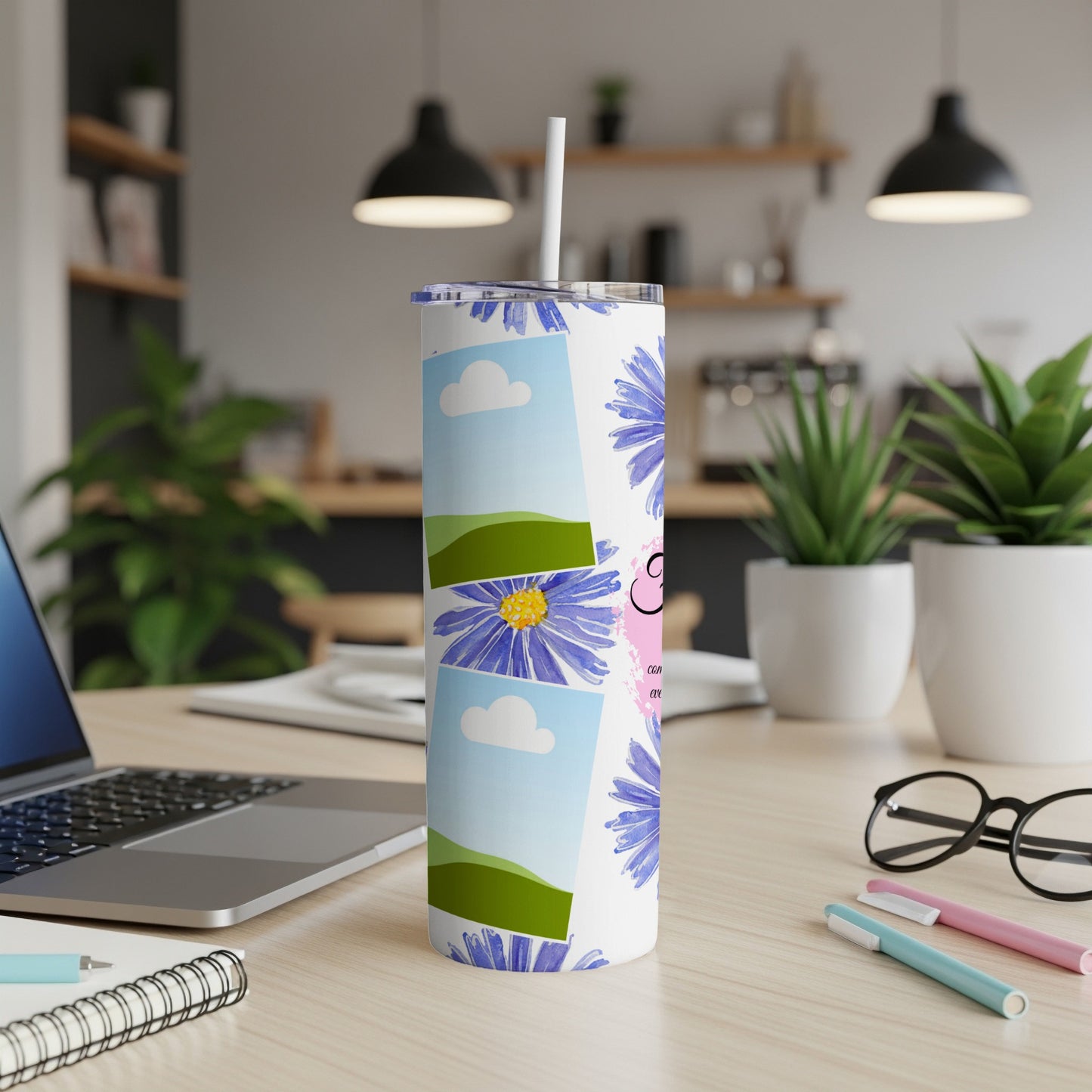 White tumbler with blue flowers, sky, and green hill photo collage.
