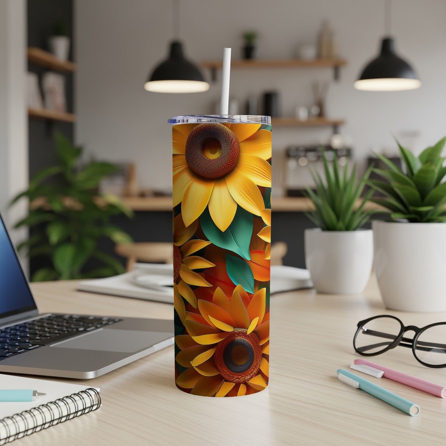 Sunflower pattern tumbler with straw on a desk.