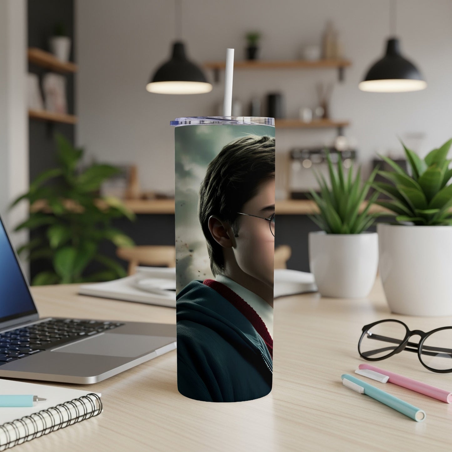 Harry Potter tumbler with white straw on a desk with a laptop and pens.