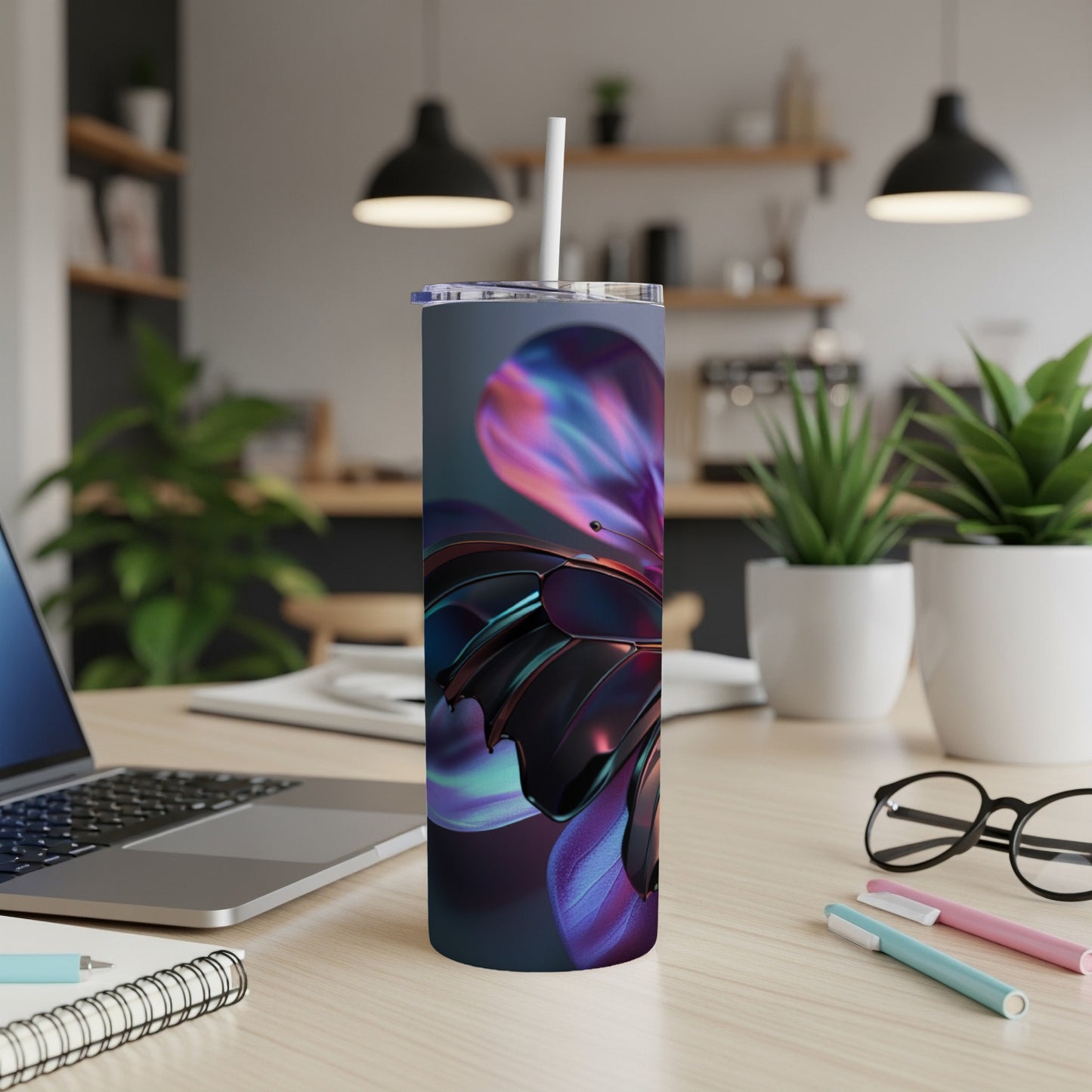 Tumbler with iridescent butterfly wing pattern on desk with laptop and pens.