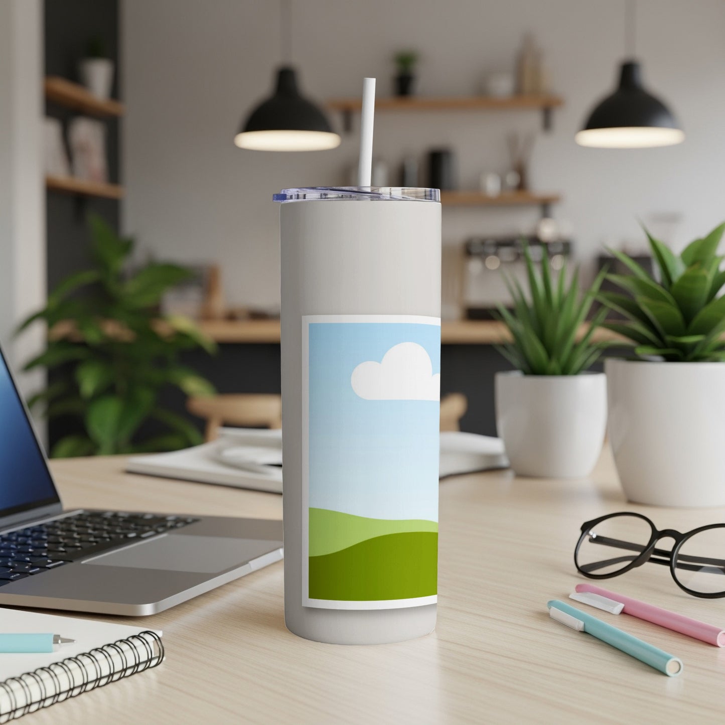 White tumbler with straw and a graphic of a blue sky with clouds and green hills.