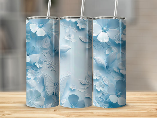 Three blue floral tumblers with butterfly accents on a wooden surface.