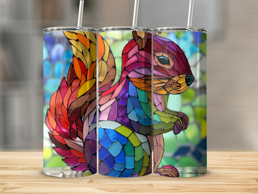 Stained glass squirrel tumbler with straw, vibrant colors, against a blurred background.