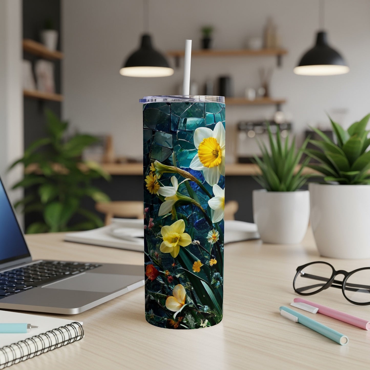 White and yellow daffodils on a dark, tiled tumbler with a straw.