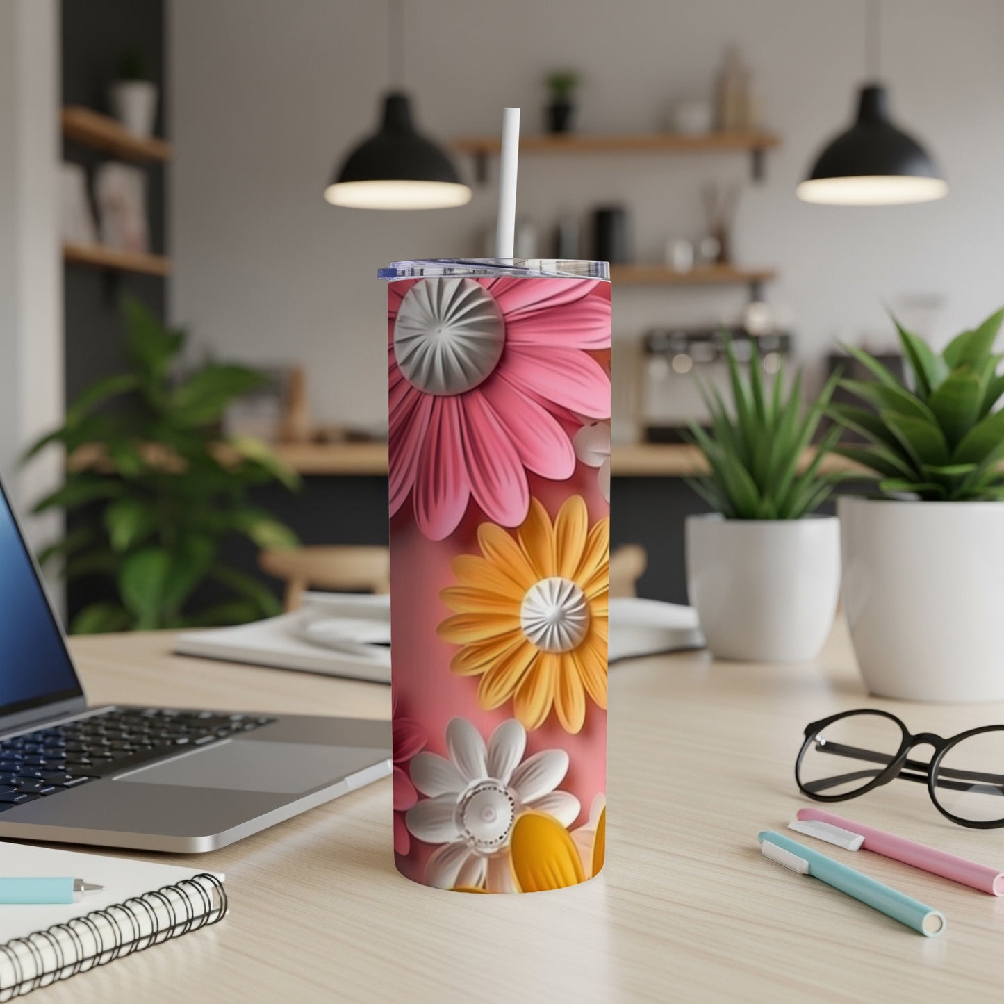 Pink and orange floral tumbler with white lid and straw on desk.