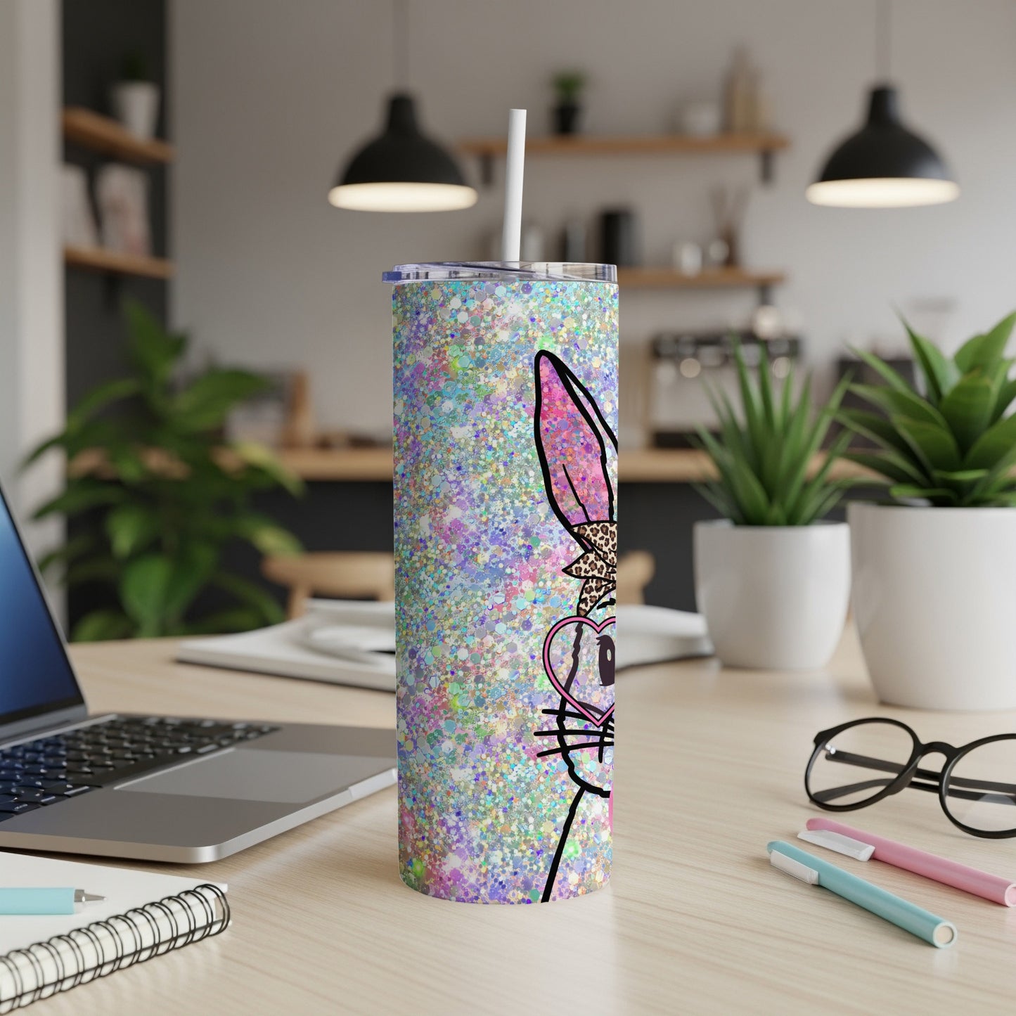 Glittery bunny tumbler with straw on a desk.