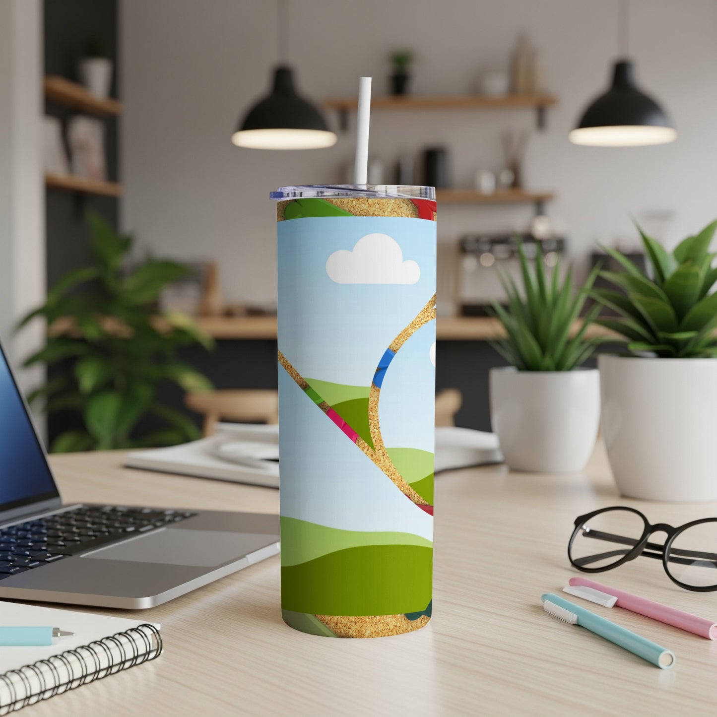 Tall tumbler with a colorful cartoon landscape design and a straw.