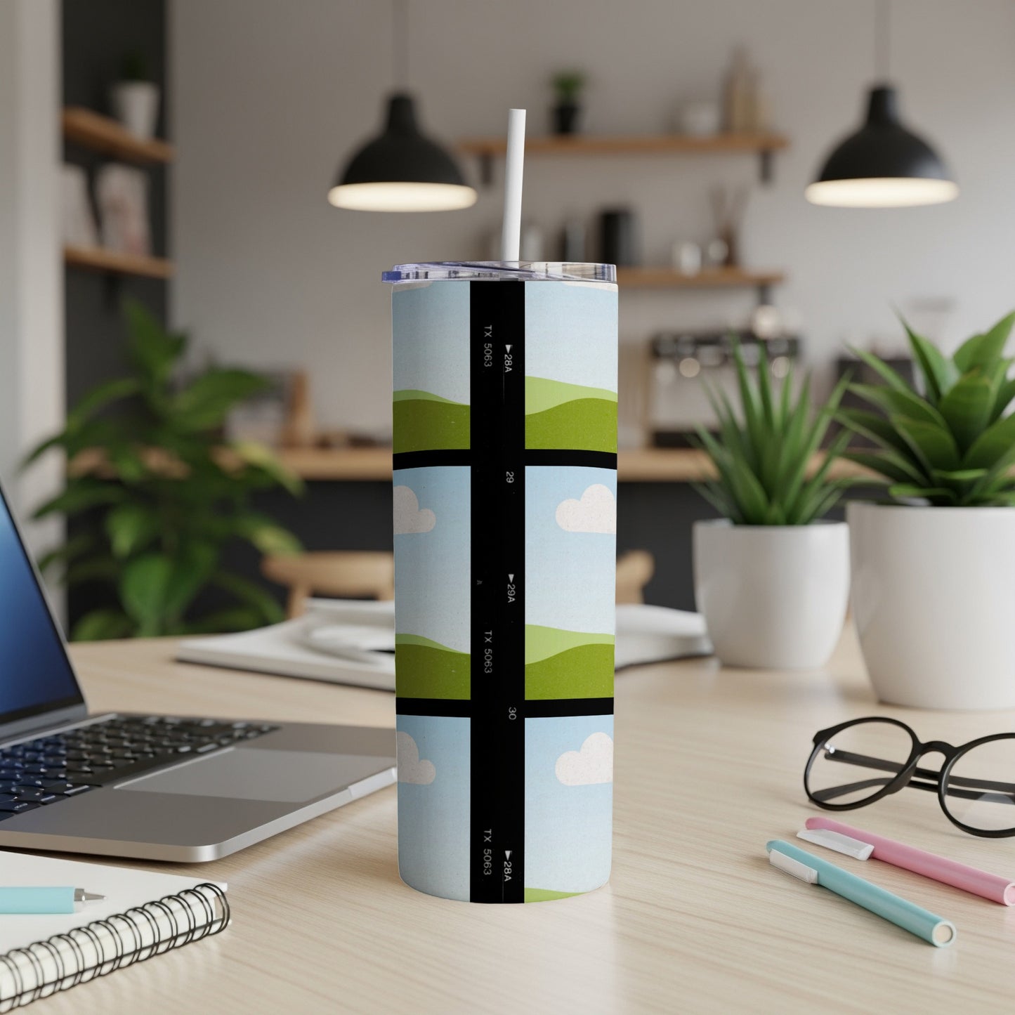 Tumbler with film strip design of green hills and clouds, includes text "TX 5063".