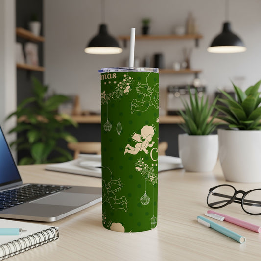 Green tumbler with white Christmas angels and ornaments, on a desk.