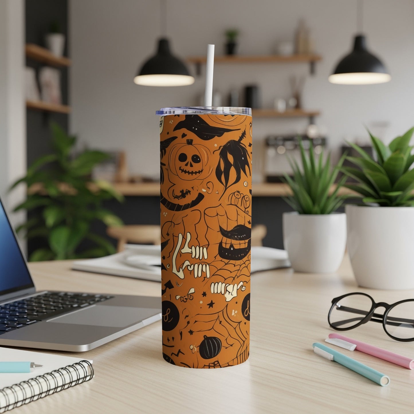 Orange tumbler with Halloween doodles, including pumpkins, skulls, and bats.