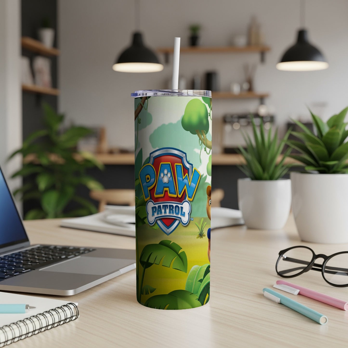 Paw Patrol tumbler with jungle scene and laptop on desk.