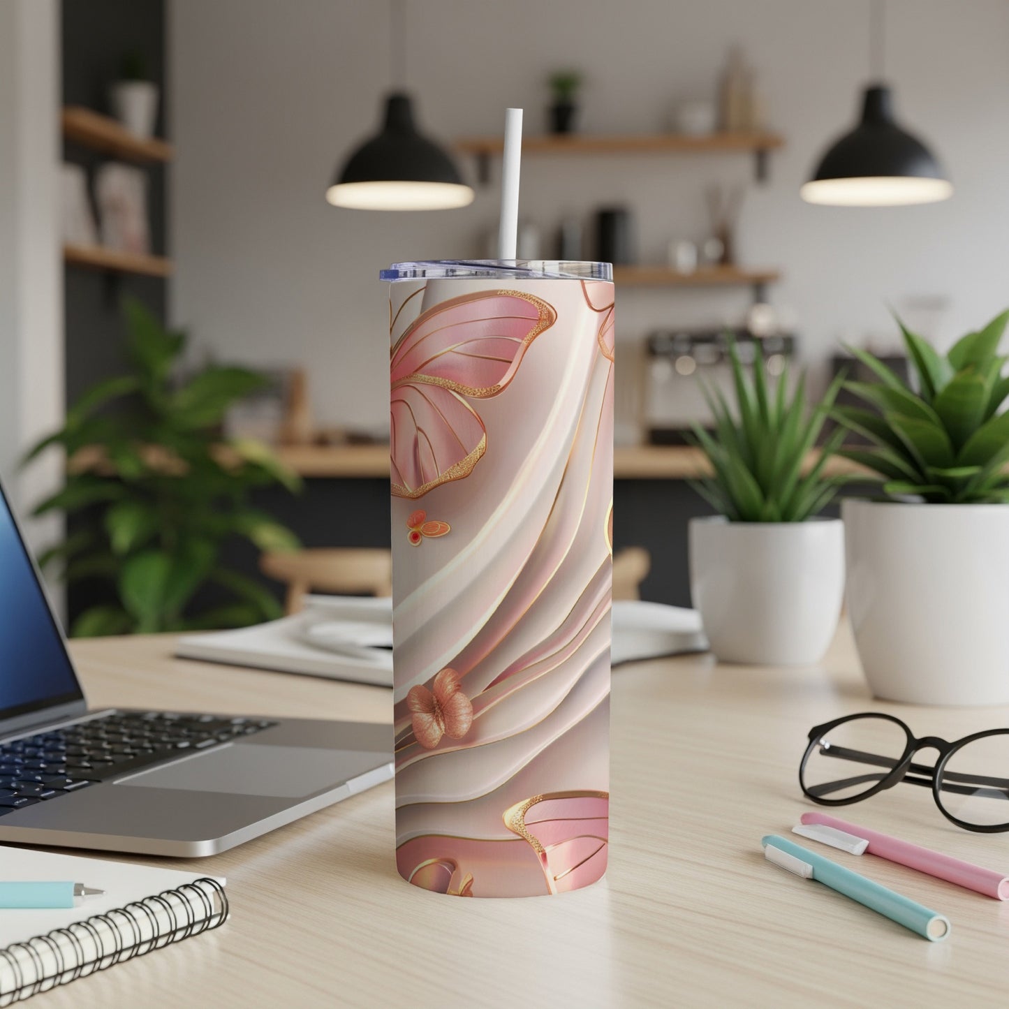Pink and gold floral tumbler with straw on desk.