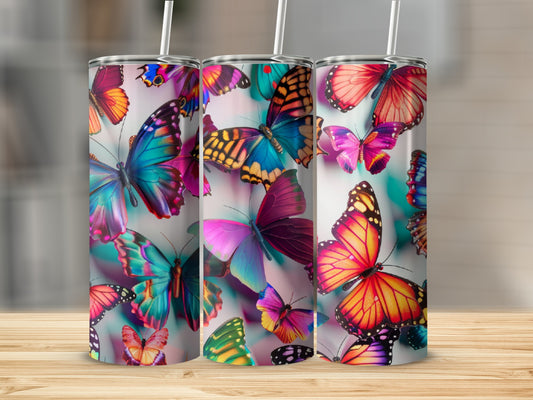 Three tumblers with colorful butterfly designs, arranged on a wooden surface.