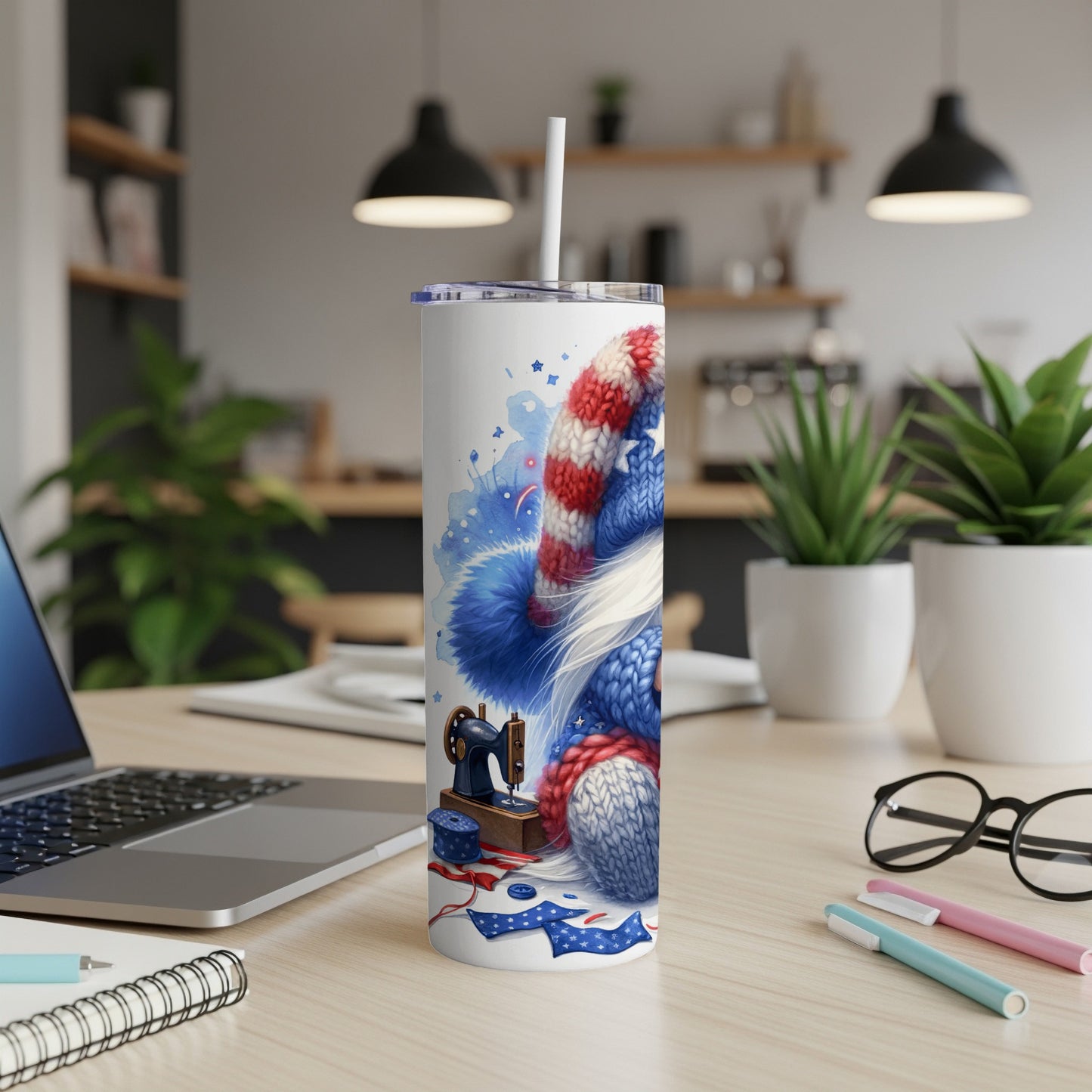 White tumbler with patriotic knitting and sewing supplies on a desk.