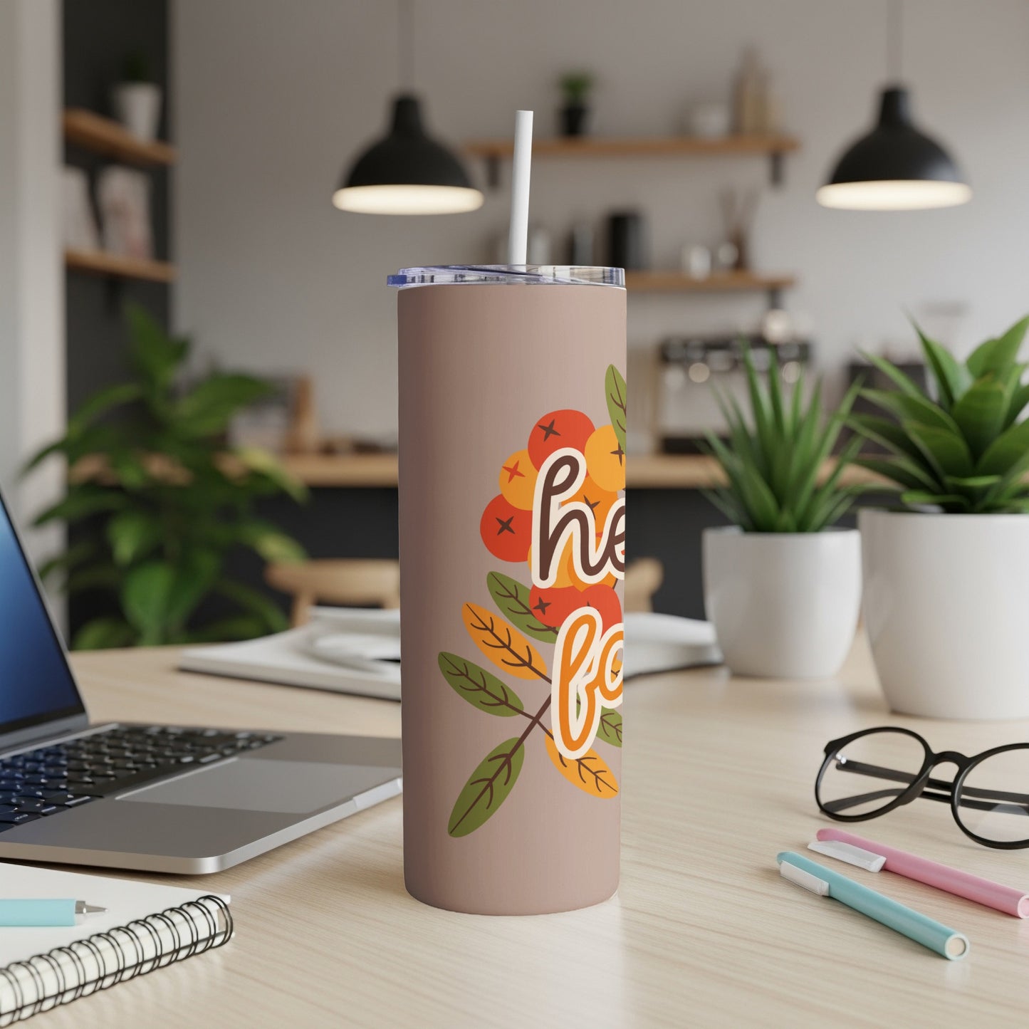 Beige tumbler with "hello fall" text and autumn leaves illustration.