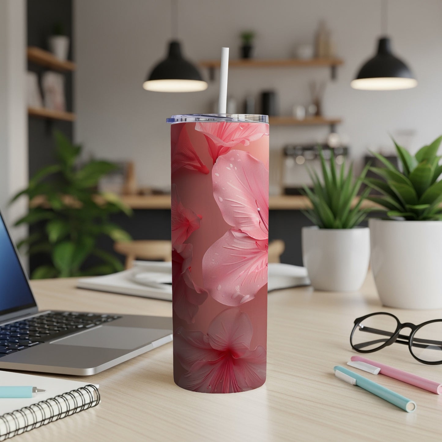 Pink hibiscus flowers on a skinny tumbler with a straw.