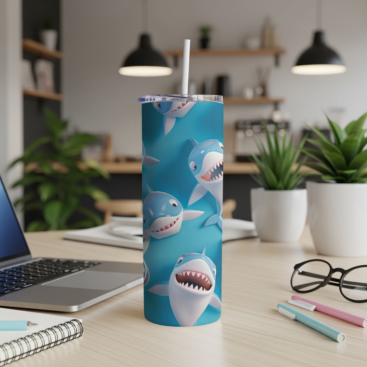 Tumbler with cartoon sharks on a blue background, with a white straw.
