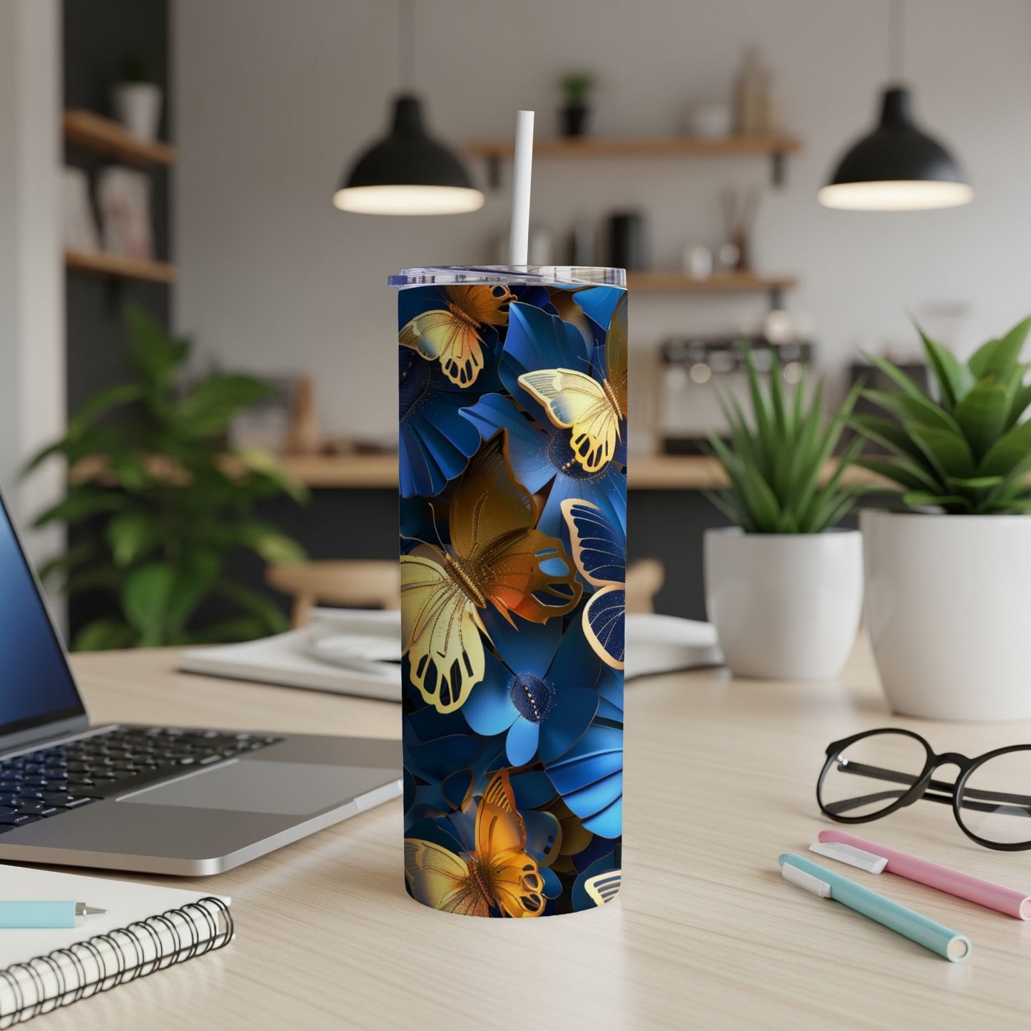 Tumbler with golden butterflies and blue floral design on a desk.