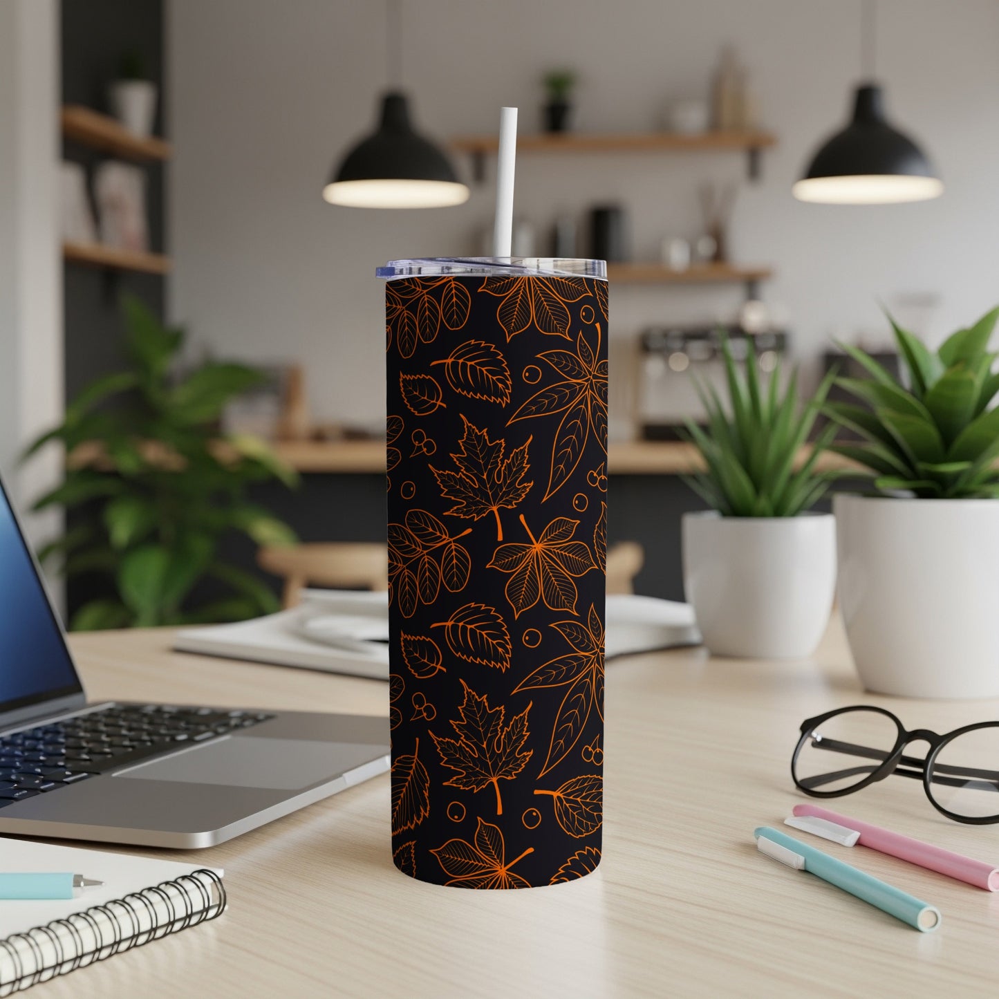 Orange leaf pattern on a black stainless steel tumbler with a white lid and straw.