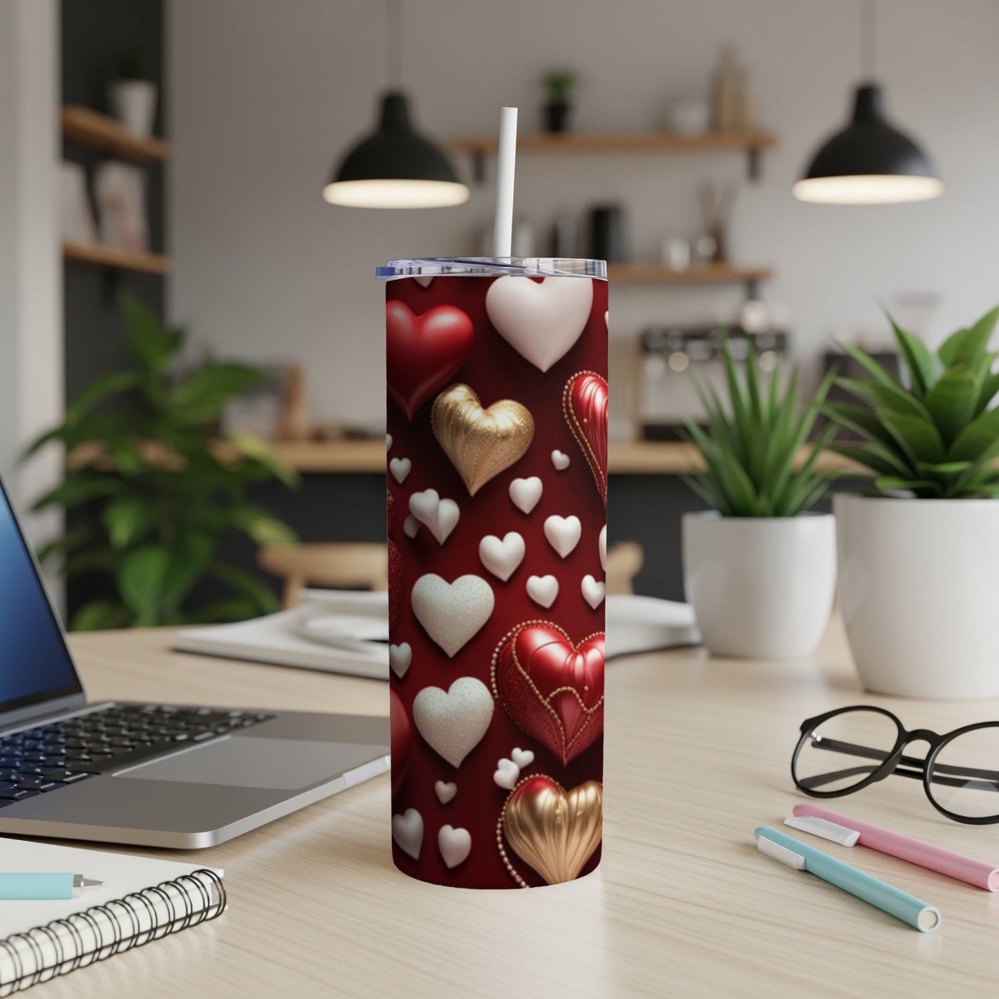 Red tumbler with white and gold hearts, straw, on a desk.