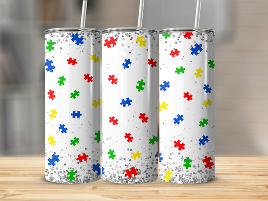 Three skinny tumblers with a colorful autism puzzle piece pattern and silver glitter.
