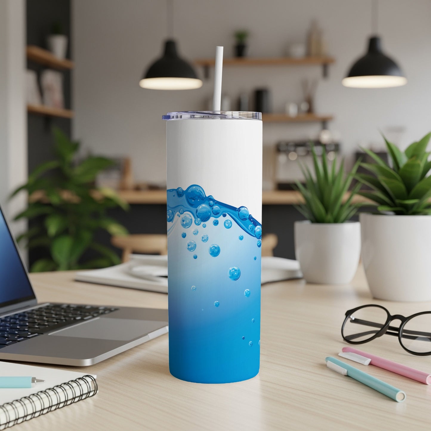 White tumbler with blue wave and bubble design on desk.