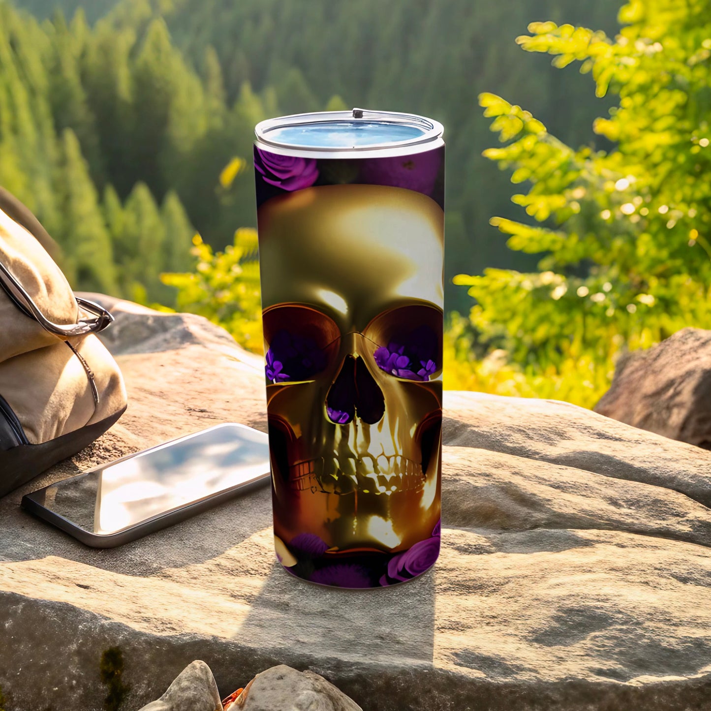 Gold skull tumbler with purple floral accents on a rock.