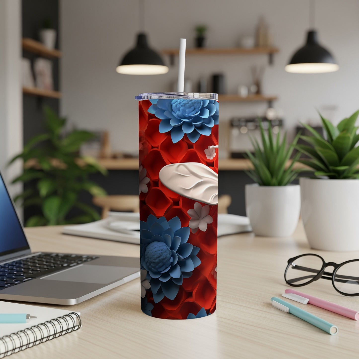 Red and blue floral tumbler with white accents on a desk.