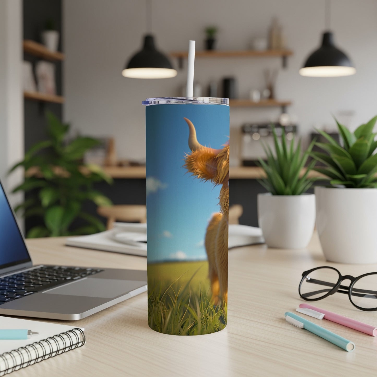 Highland cow on a tumbler with a laptop and office supplies.