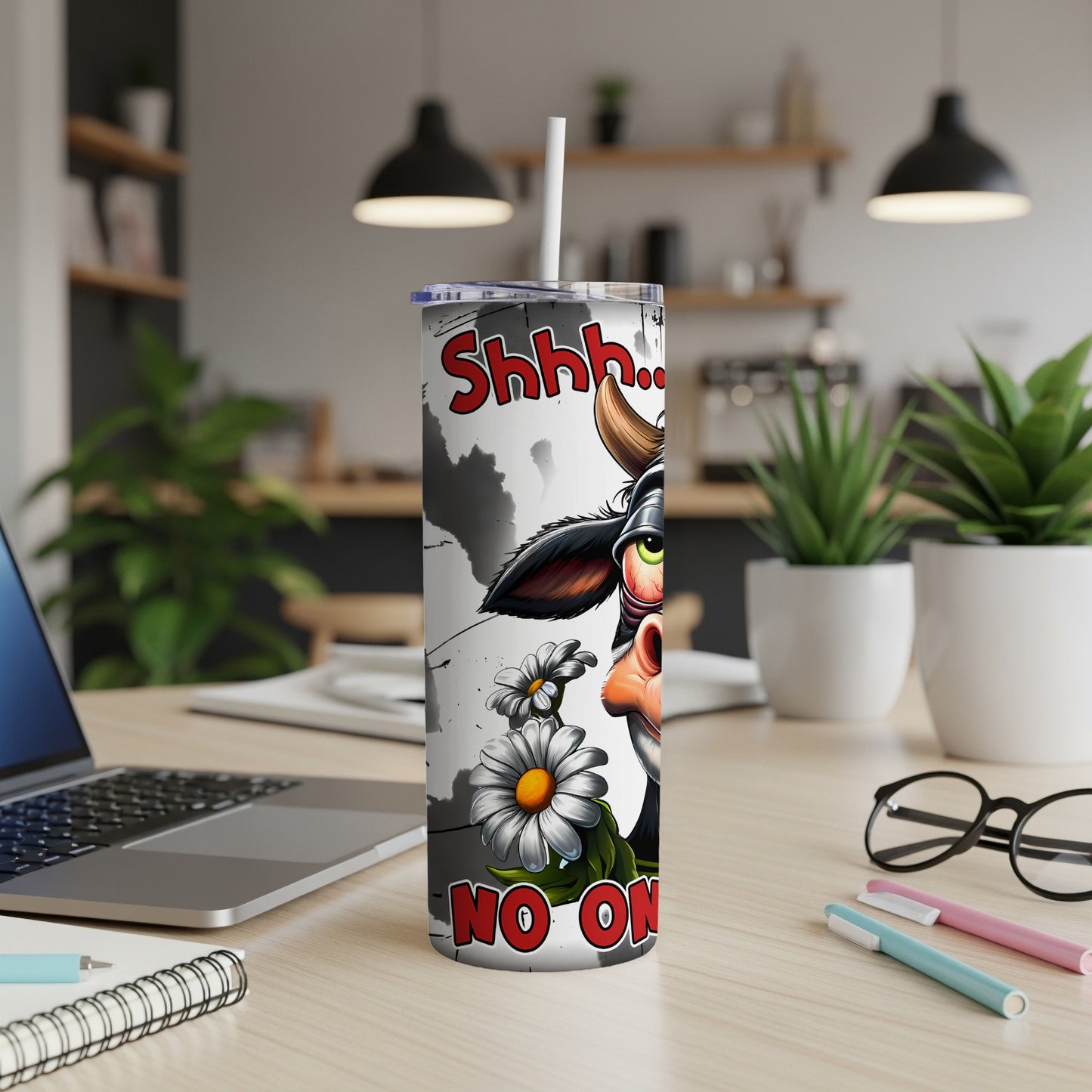 Humorous cow tumbler with "Shhh... No One" text on a desk.