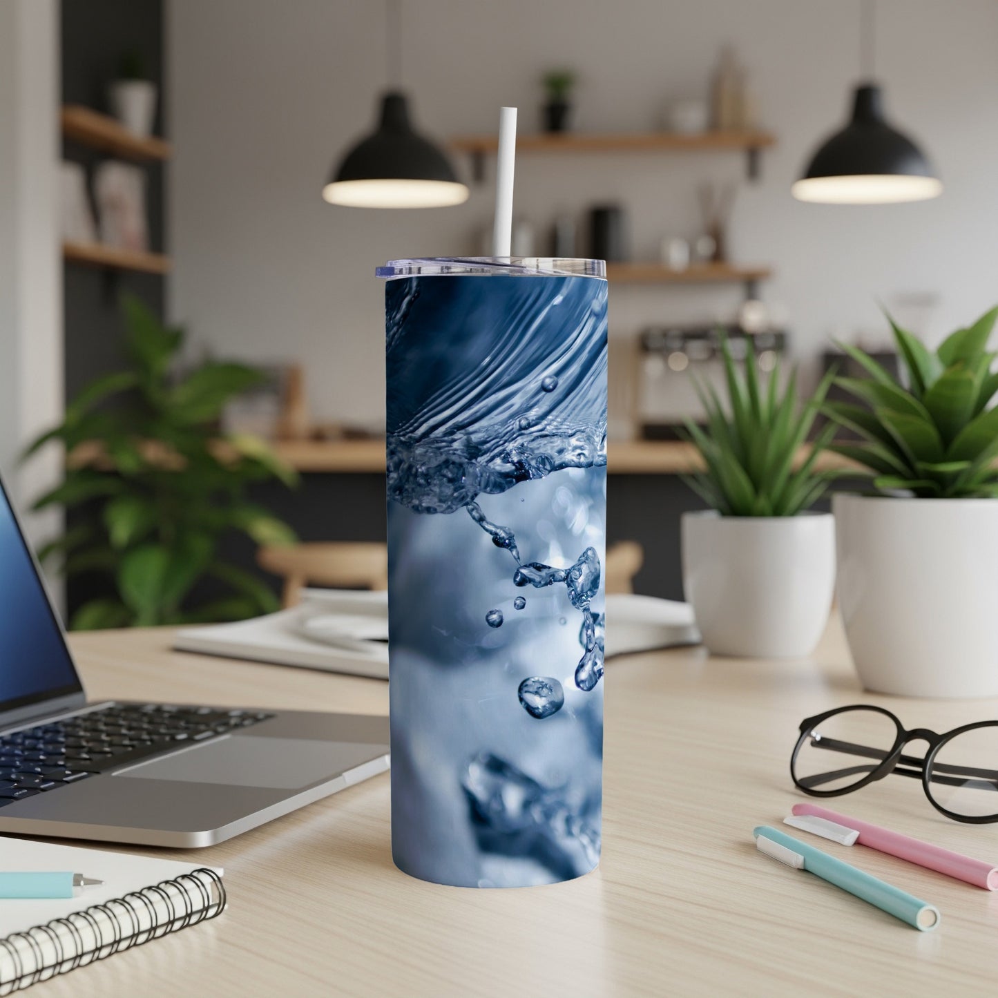 Tumbler with water splash design on a desk with laptop and office supplies.