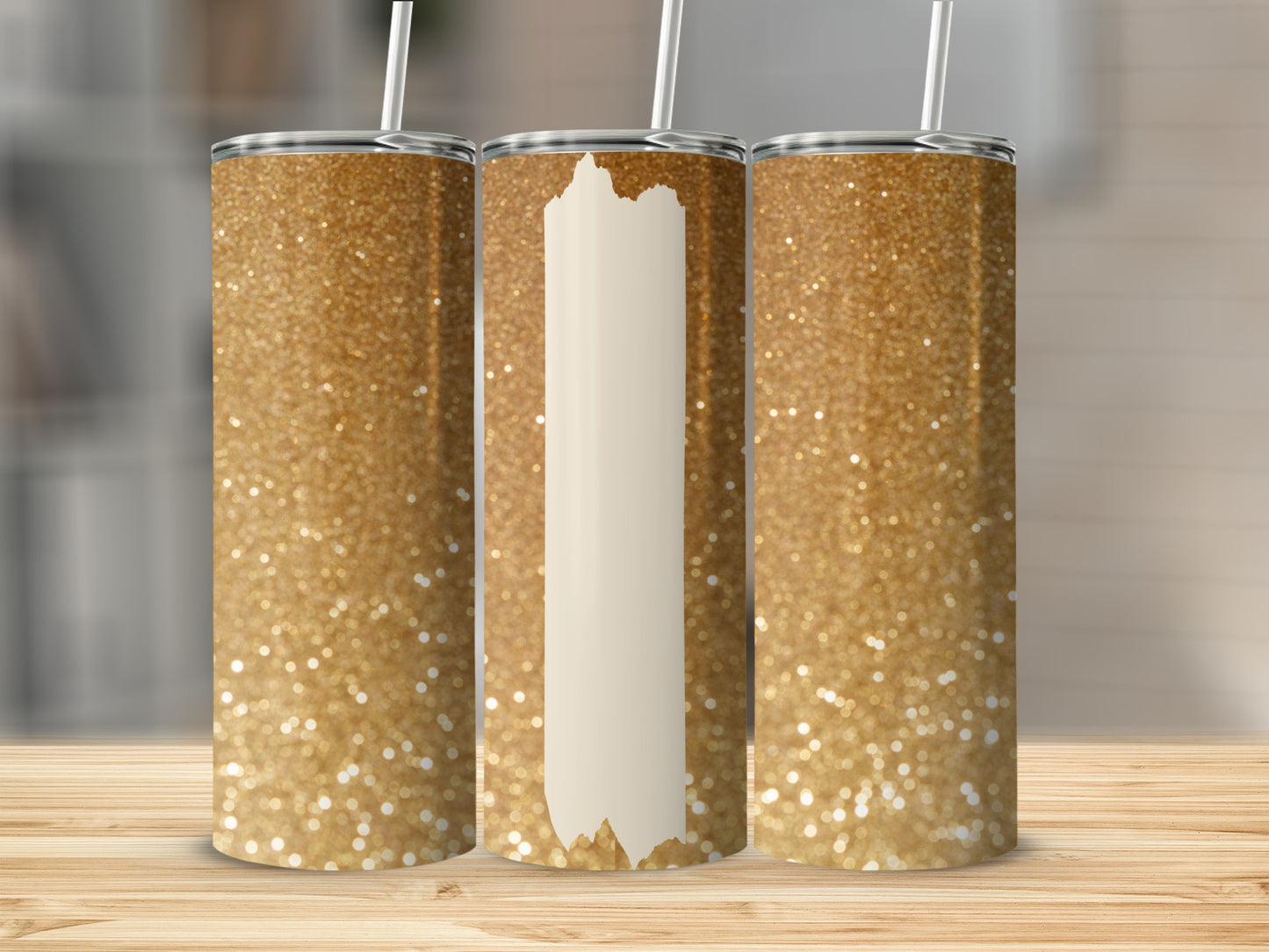 Three glittery gold tumblers with white straws on a wooden surface.