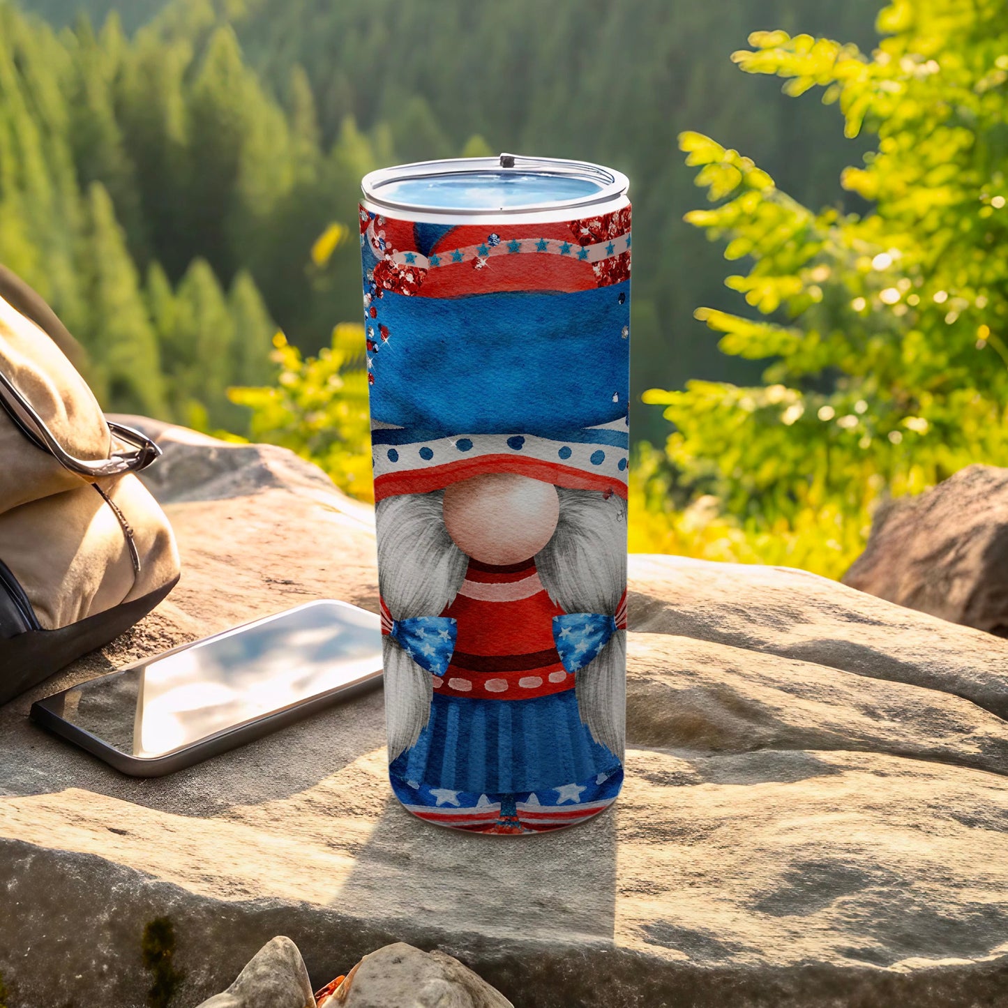 Patriotic gnome tumbler with stars and stripes on outdoor rocky surface.