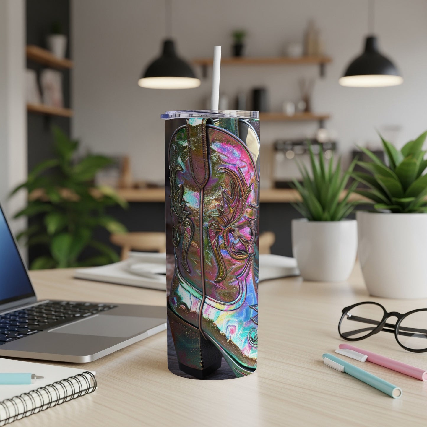 Tall, iridescent cowboy boot tumbler with straw on a desk.