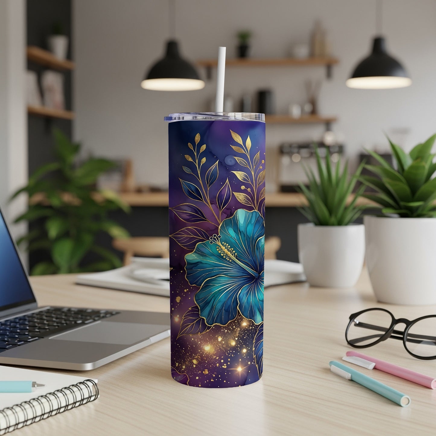 Purple tumbler with blue hibiscus flower and gold accents, on a desk.