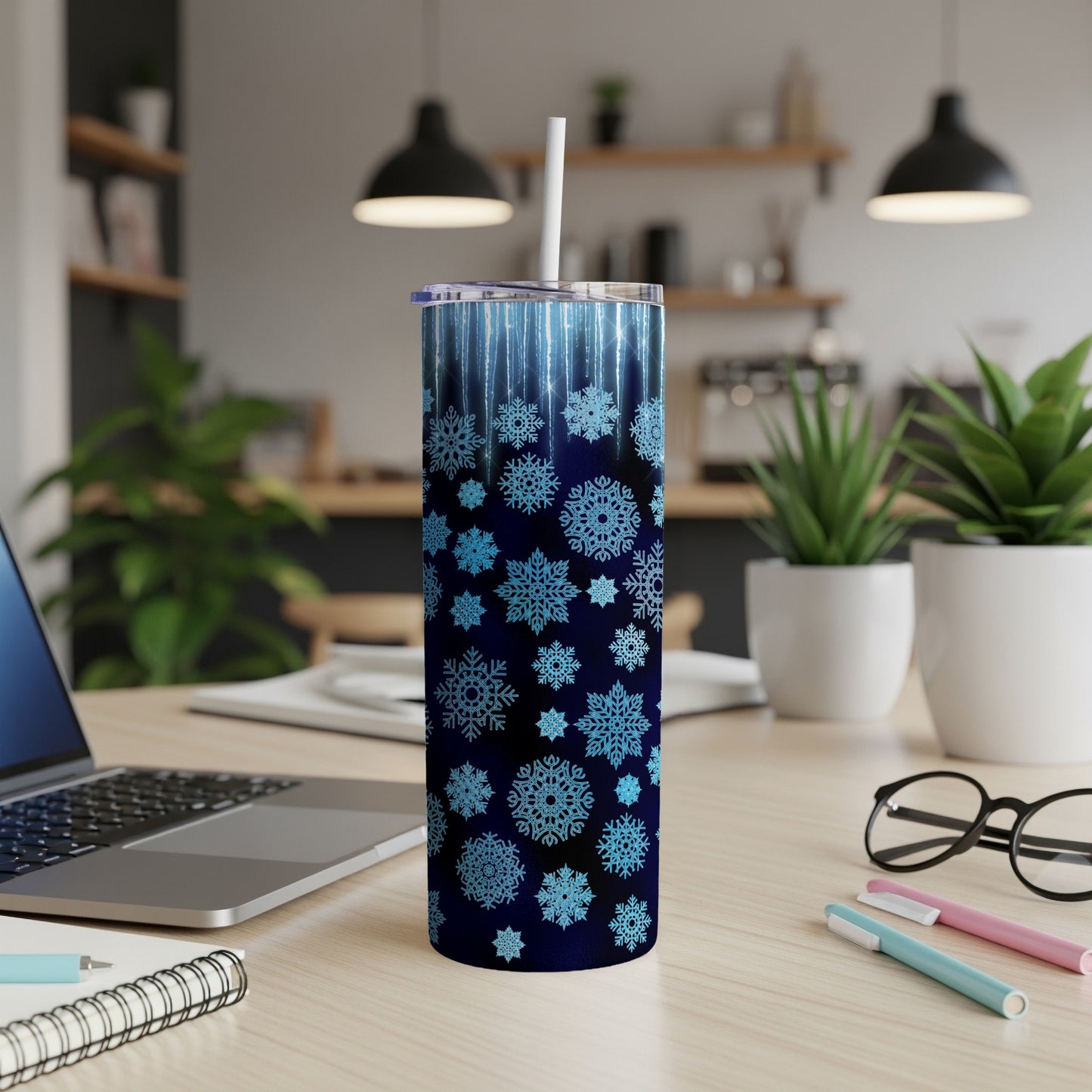 Blue snowflake patterned tumbler with white straw on a desk.
