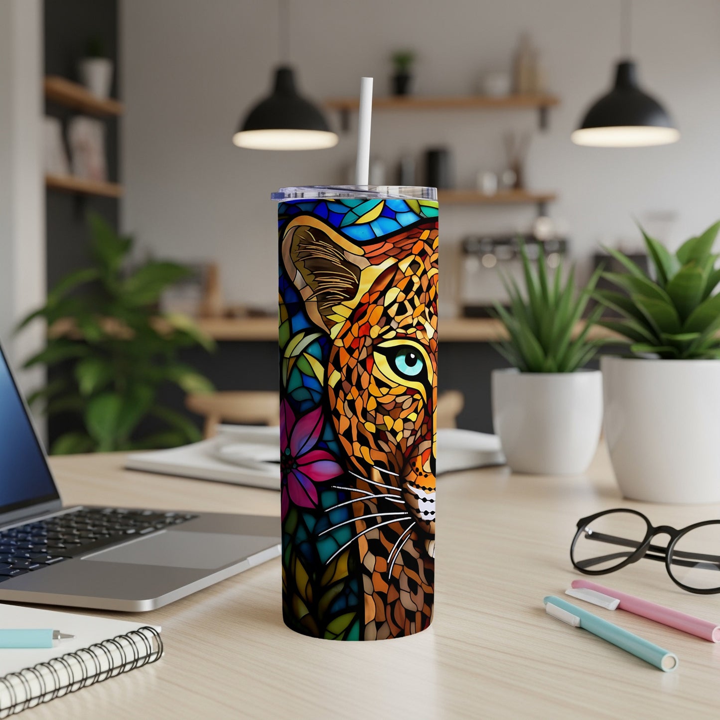 Stained glass leopard face tumbler with straw on a desk.