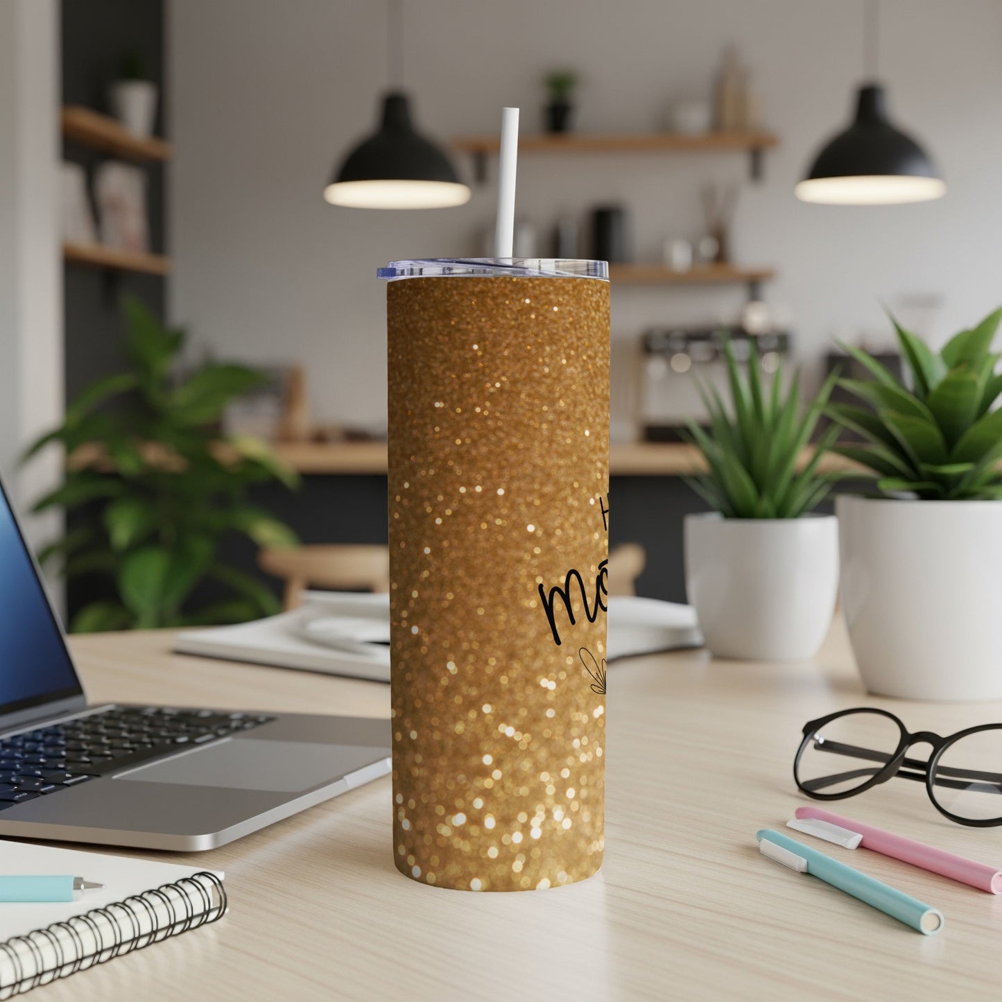 Gold glitter tumbler with "Mom" text on a desk with laptop.