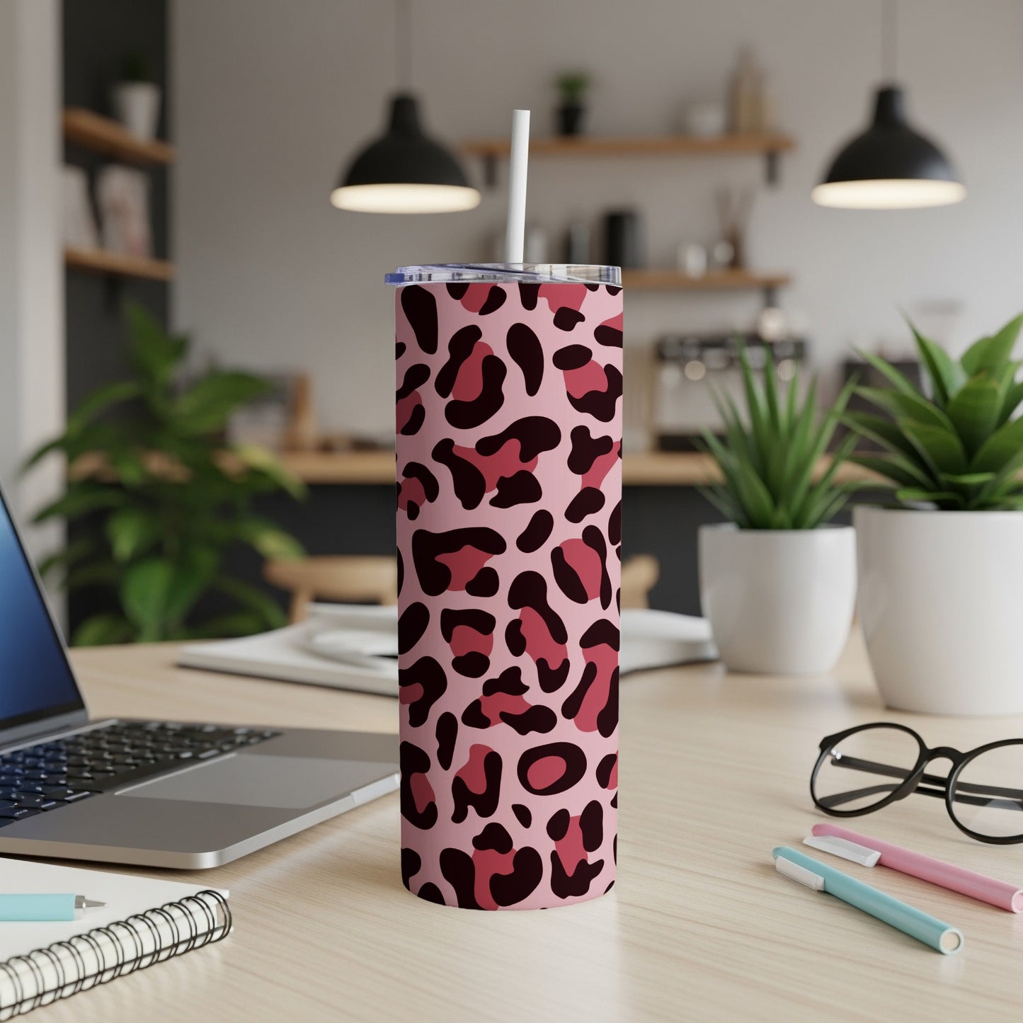 Pink and dark red leopard print tumbler with white straw on wooden desk.