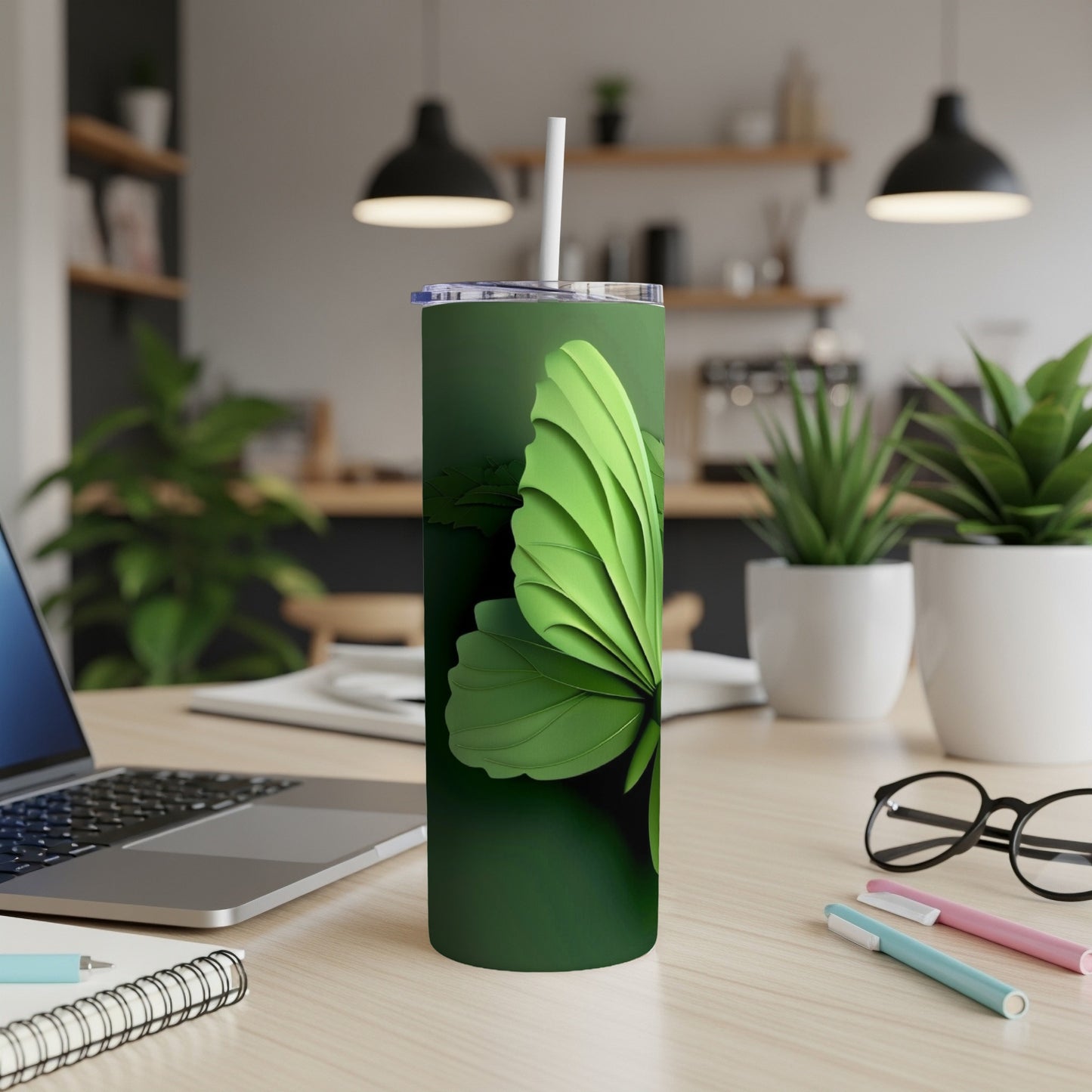 Green butterfly tumbler with straw on a desk next to a laptop.