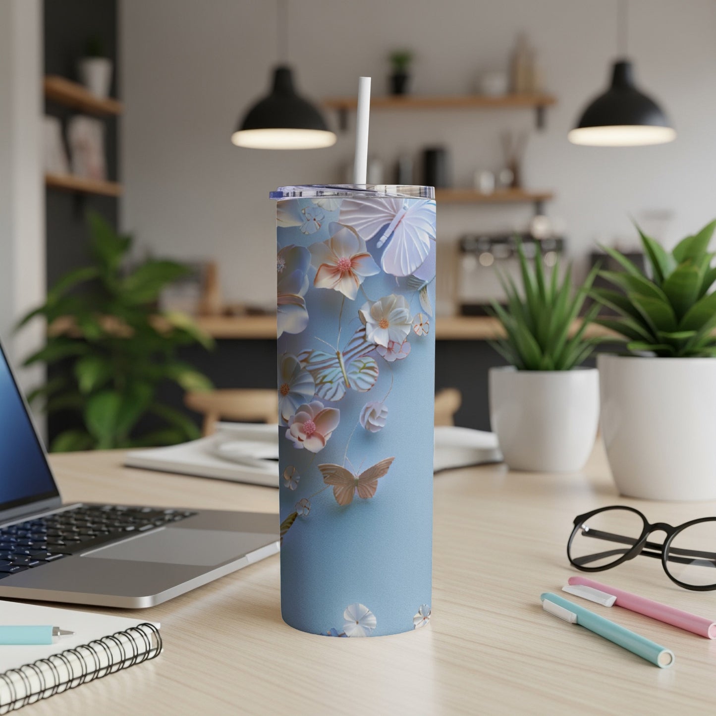 Blue tumbler with butterflies and floral designs on a desk.