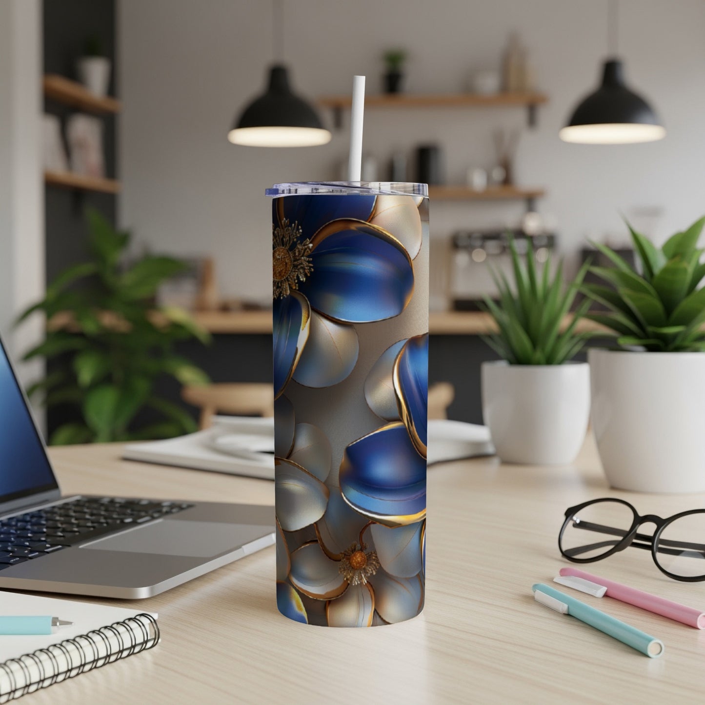 Floral tumbler with blue and gold petals on a desk.