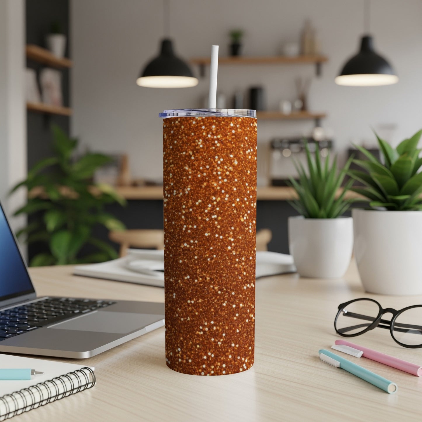 Glittery orange skinny tumbler with white straw on desk.