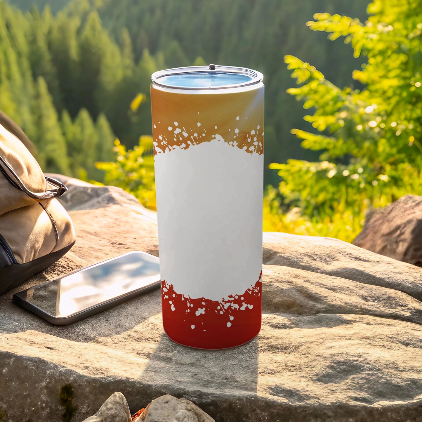 White and red abstract design tumbler on a rock with a phone and backpack.