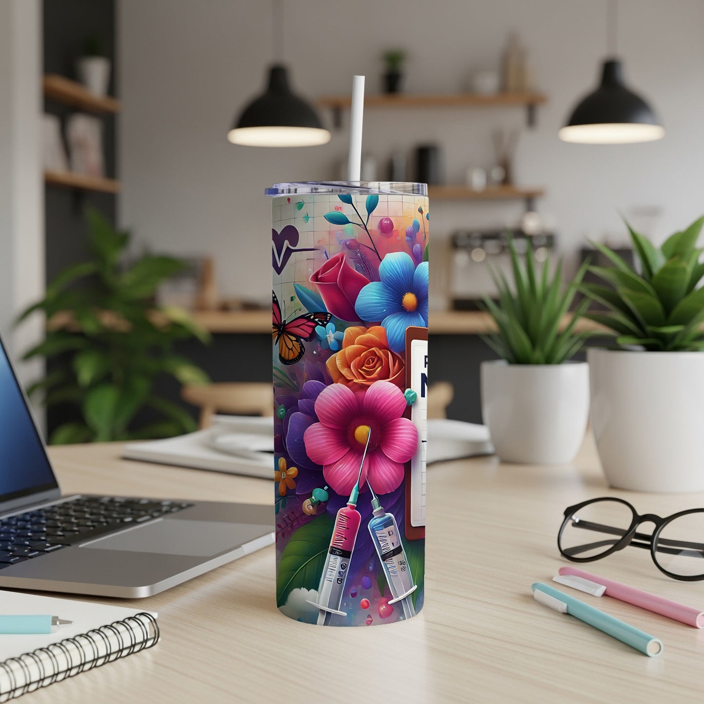 Tall tumbler with floral design and medical syringes, on a desk.