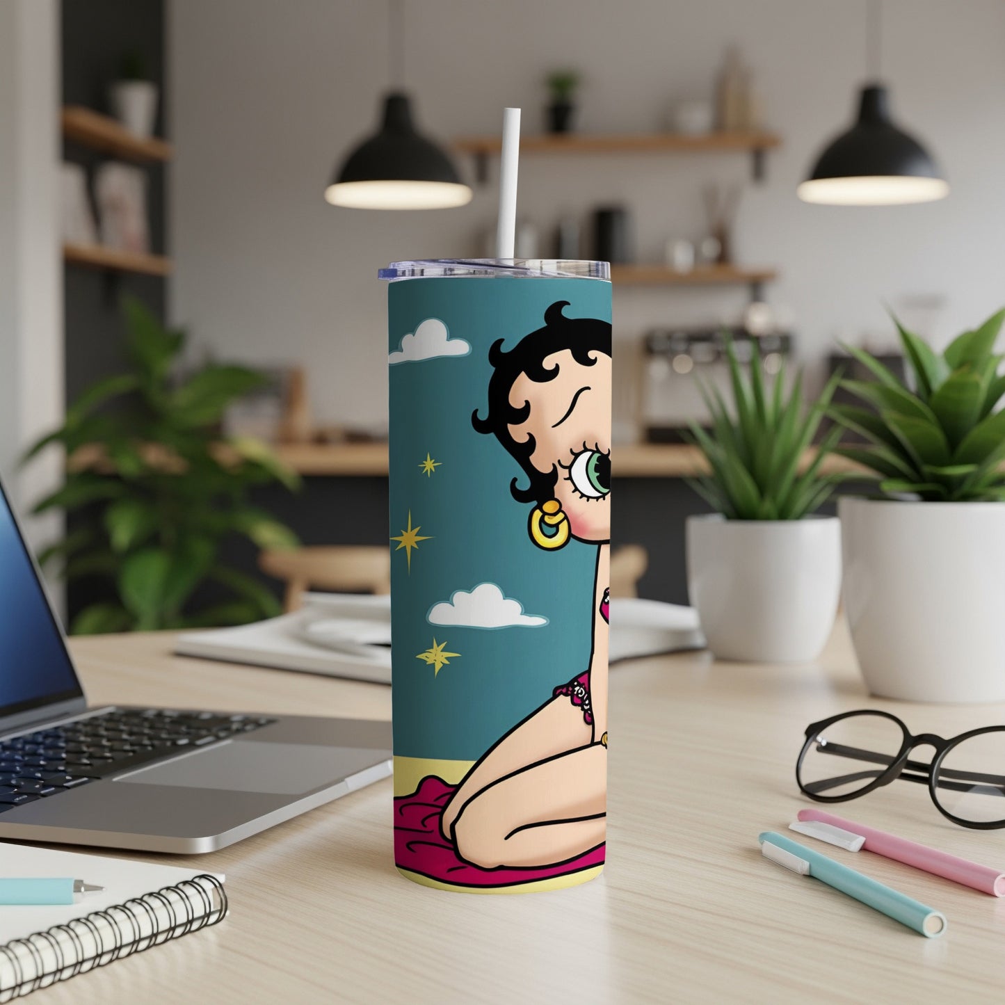 Betty Boop on a teal tumbler with a straw, on a desk.