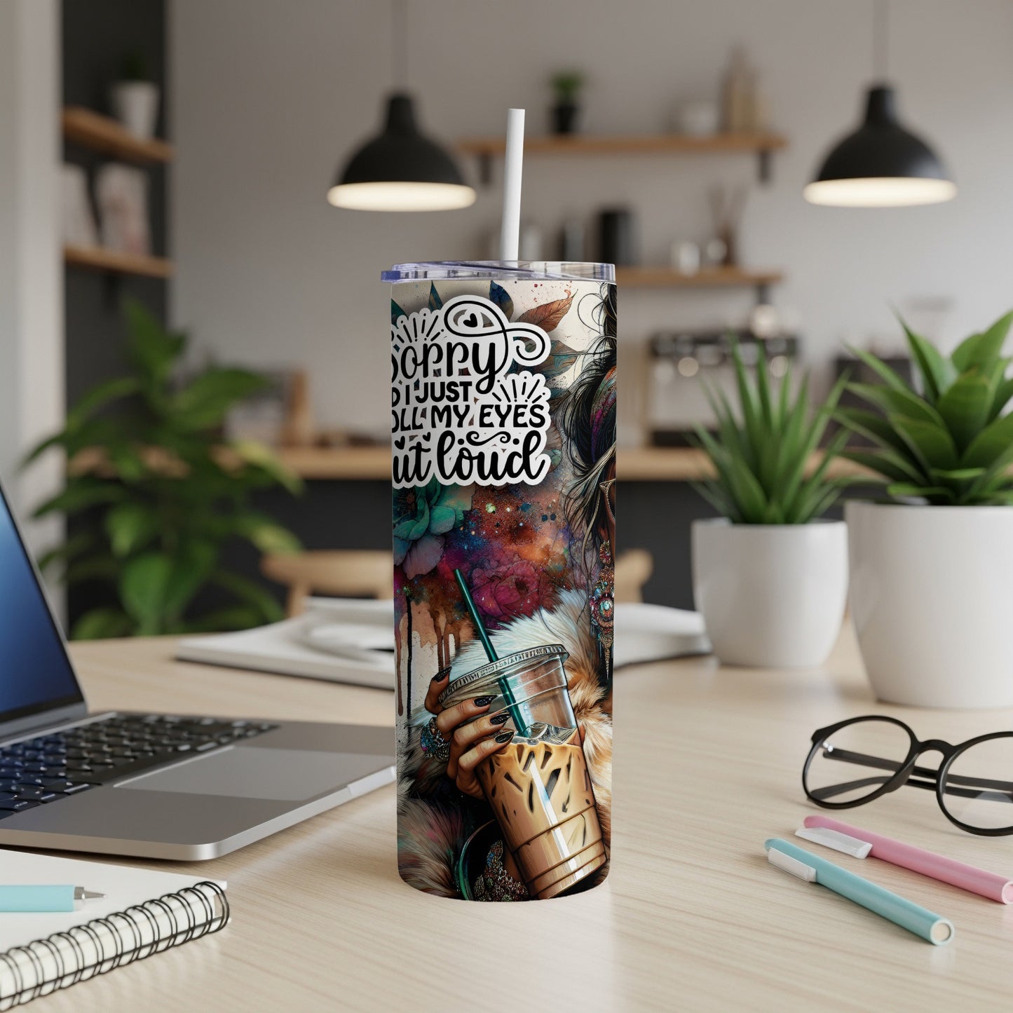 Woman's hand holding iced coffee tumbler with abstract art and text.