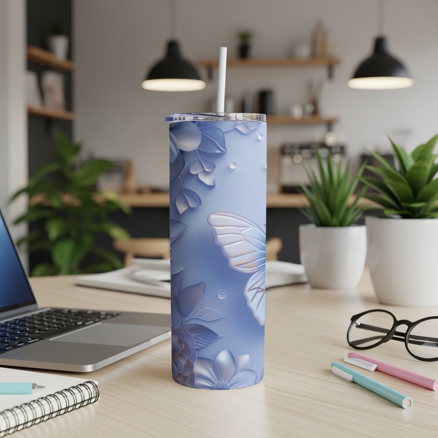Blue floral tumbler with butterfly design and white straw on desk.